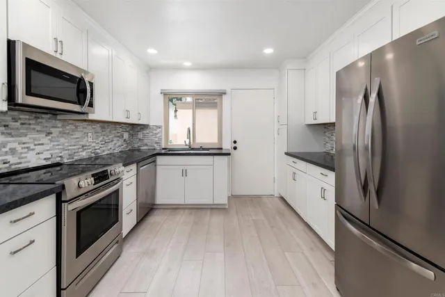 a kitchen with stainless steel appliances kitchen island granite countertop a stove a sink and a microwave