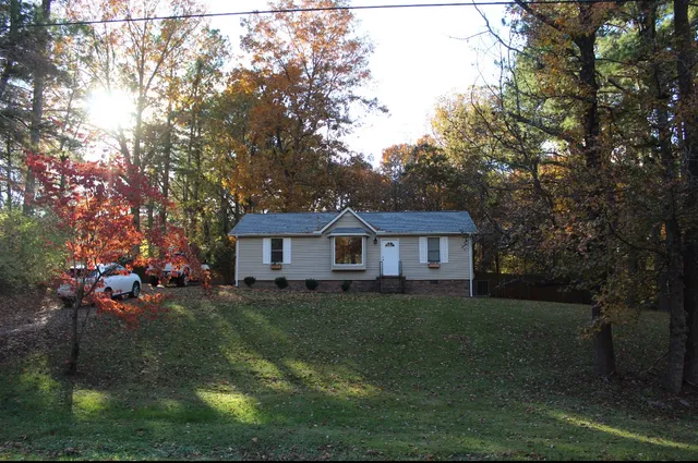 a view of a yard in front of a house with large trees