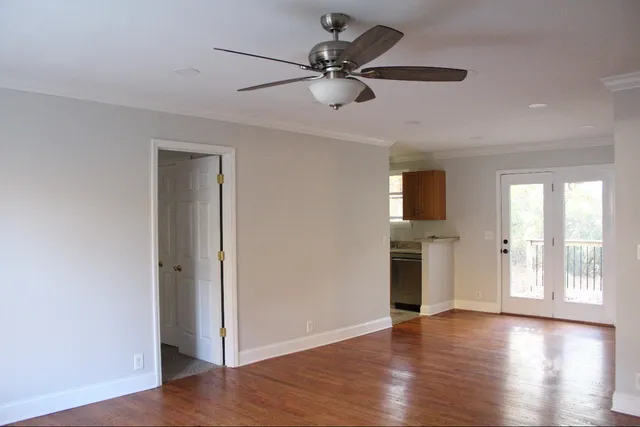 a view of an empty room with window and wooden floor