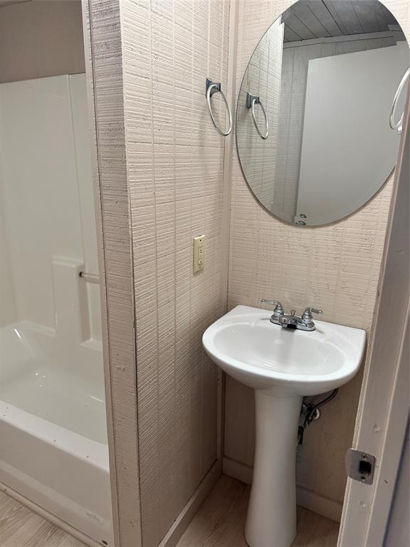 2590 Rock Ridge Road Lucas, TX 75002 - Photo 21 of 25 Compact bathroom featuring a white pedestal sink with chrome fixtures, a frameless oval mirror, and a white shower-over-tub combination