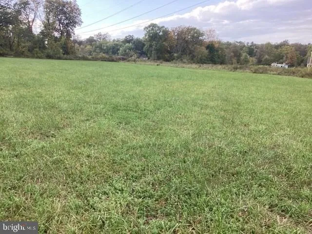 a view of a green field with wooden fence