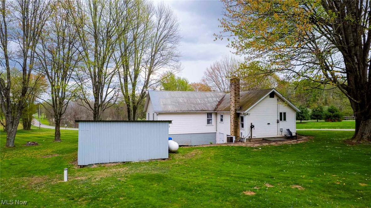 7997 Chestnut Ridge Road Northwest Beach City, OH 44608 - Photo 29 of 31 Rear view of house featuring a lawn, metal roof, central AC, and an outdoor structure