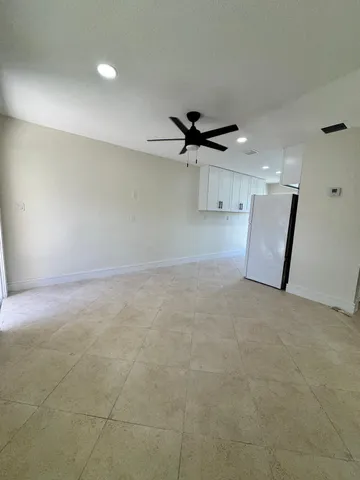 an empty room with a ceiling fan and window