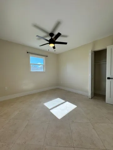 an empty room with windows and ceiling fan