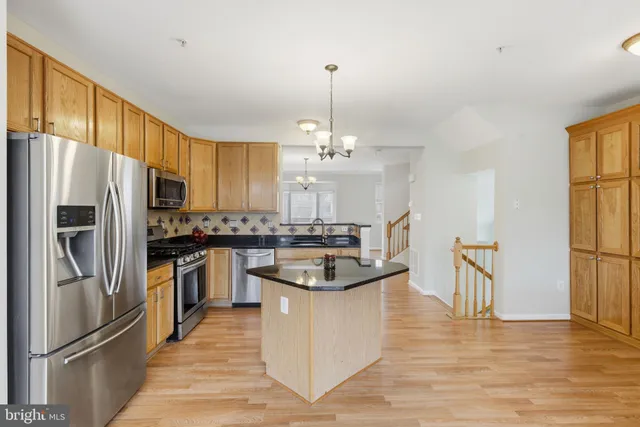 a kitchen with stainless steel appliances granite countertop a refrigerator a sink dishwasher a oven with white cabinets and wooden floor