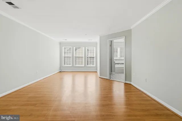 a view of an empty room with window and wooden floor