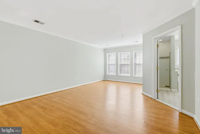 a view of an empty room with glass door and wooden floor