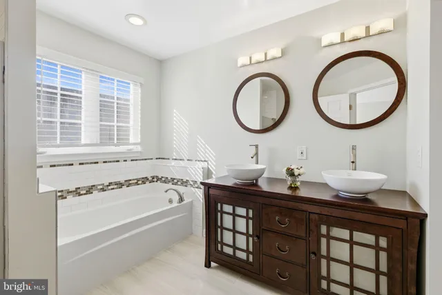 a bathroom with a granite countertop double vanity sink and a bathtub