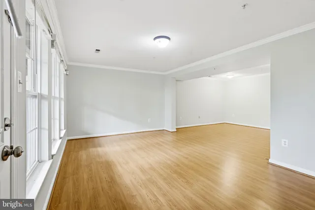 a view of empty room with wooden floor and fan