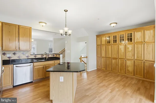 a kitchen with stainless steel appliances granite countertop a sink a stove and a wooden floors
