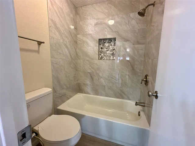 a white toilet sitting next to a bath tub and a shower