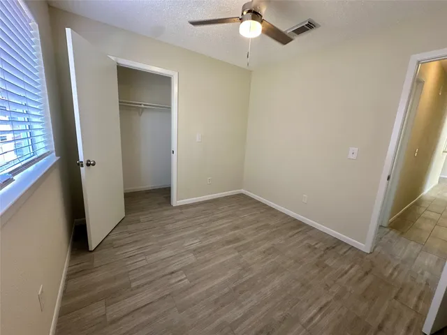 an empty room with wooden floor cabinet and windows
