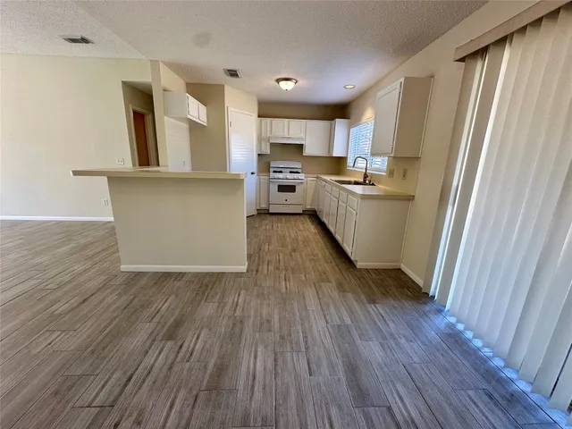 a kitchen with stainless steel appliances granite countertop a refrigerator a sink dishwasher a stove and white countertops with wooden floor