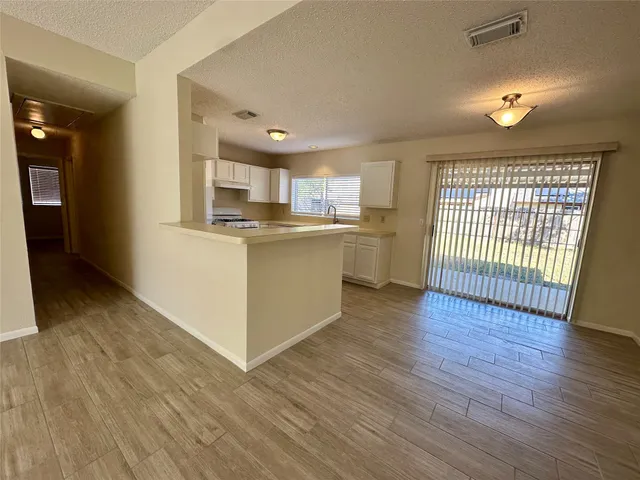 a open kitchen with cabinets wooden floor and a stainless steel appliances