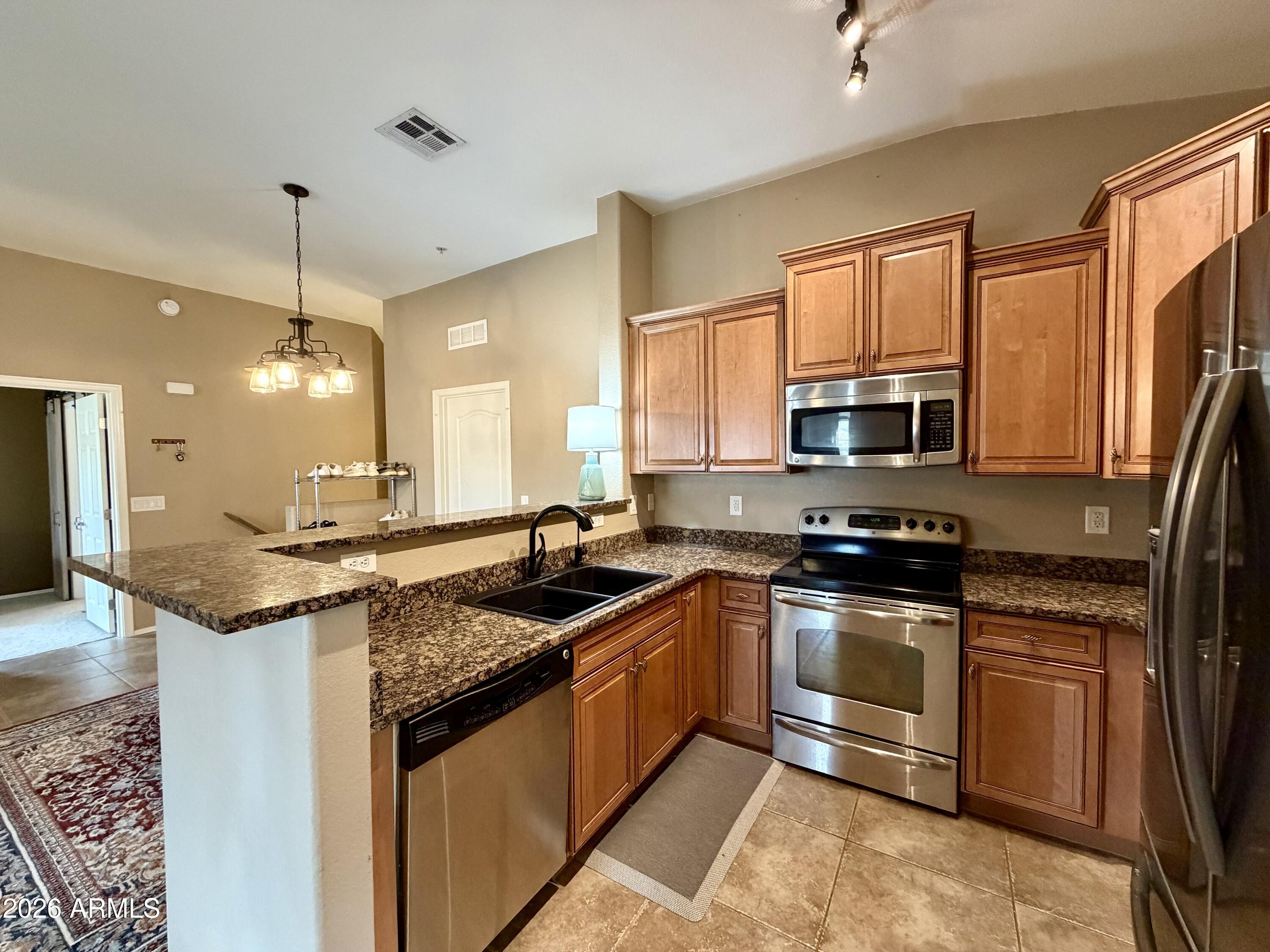 2725 East Mine Creek Road, Unit 2058 Phoenix, AZ 85024 - Photo 5 of 16 a kitchen with stainless steel appliances granite countertop a sink a stove and a microwave
