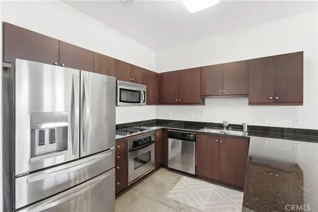 a kitchen with granite countertop a refrigerator and a stove top oven
