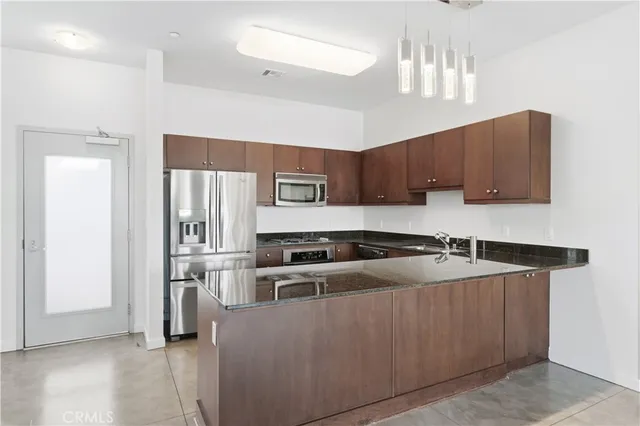 a kitchen with stainless steel appliances granite countertop a refrigerator a sink and a stove