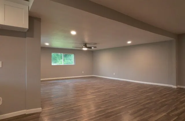 a view of an empty room with a window and wooden floor