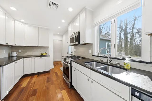 a kitchen with granite countertop a sink a counter space appliances and cabinets