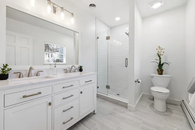 a bathroom with a granite countertop sink toilet a large mirror a shower and a bathtub