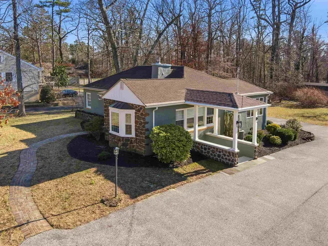a front view of a house with a garden and trees