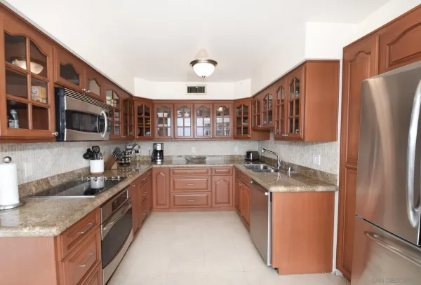 a kitchen with stainless steel appliances granite countertop a stove top oven a refrigerator a sink and dishwasher with wooden cabinets