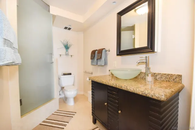 a bathroom with a granite countertop sink a toilet and a mirror