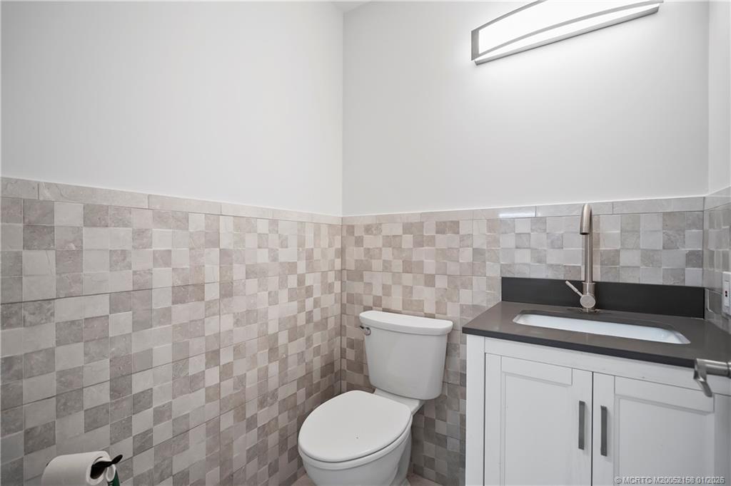 2164 Southeast St Lucie Boulevard Stuart, FL 34996 - Photo 52 of 60 a bathroom with a granite countertop toilet and a sink