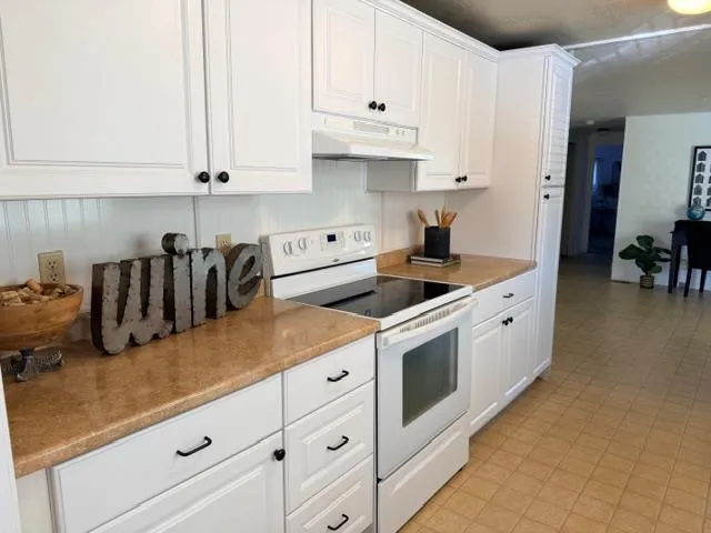 a kitchen with granite countertop a sink a stove and cabinets