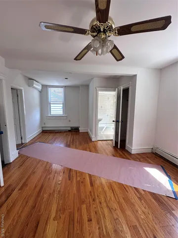 a view of an empty room with window and wooden floor