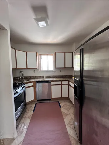 a kitchen with granite countertop a stove a sink and a refrigerator