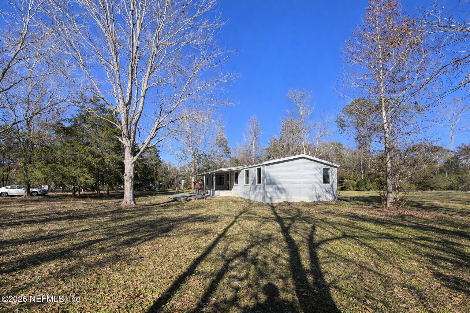 54052 Dornbush Road Callahan, FL 32011 - Photo 27 of 27 a view of a white house with a yard covered in the forest