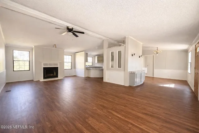 a view of a livingroom with wooden floor and a kitchen