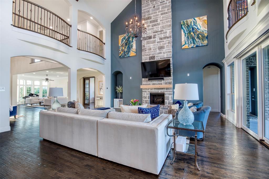 901 Inverness Court Lucas, TX 75002 - Photo 12 of 40 Living area featuring arched walkways, dark wood-type flooring, a stone fireplace, a high ceiling, and recessed lighting