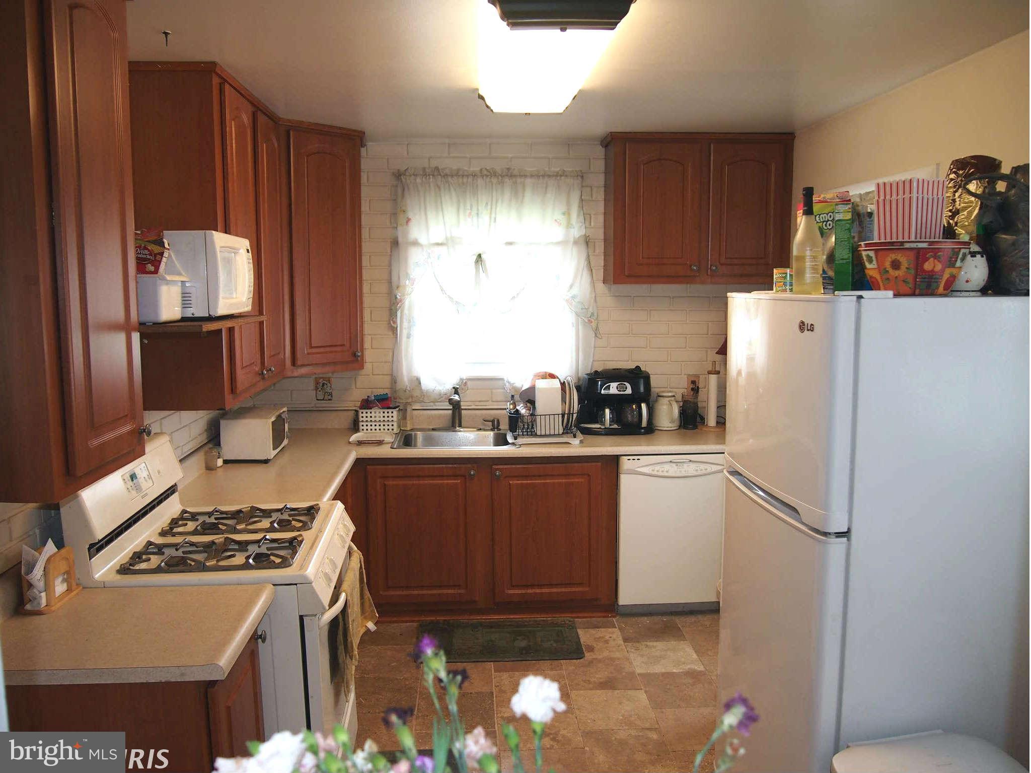 319 Holly Manor Road Baltimore, MD 21228 - Photo 2 of 17 a kitchen with a refrigerator a stove a sink and a counter
