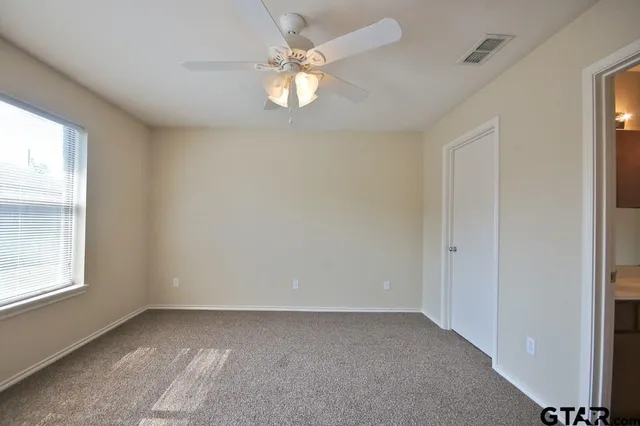 an empty room with a chandelier fan and windows