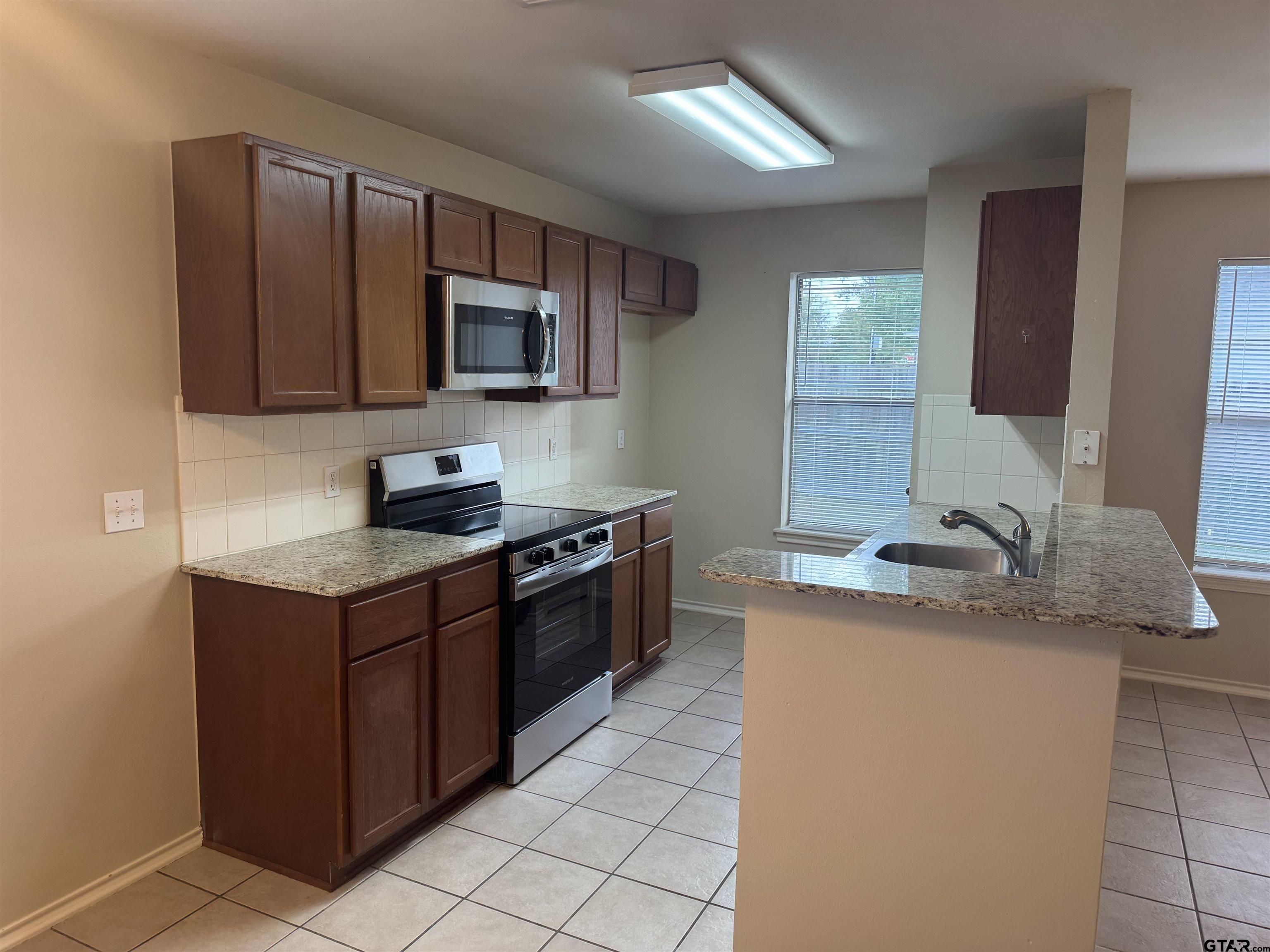 613 Hagan Road Whitehouse, TX 75791 - Photo 2 of 22 a kitchen with stainless steel appliances granite countertop a sink stove and microwave