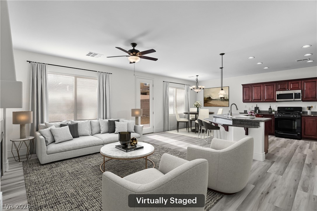 Living area with light wood-type flooring, suspended lighting, and ceiling fan