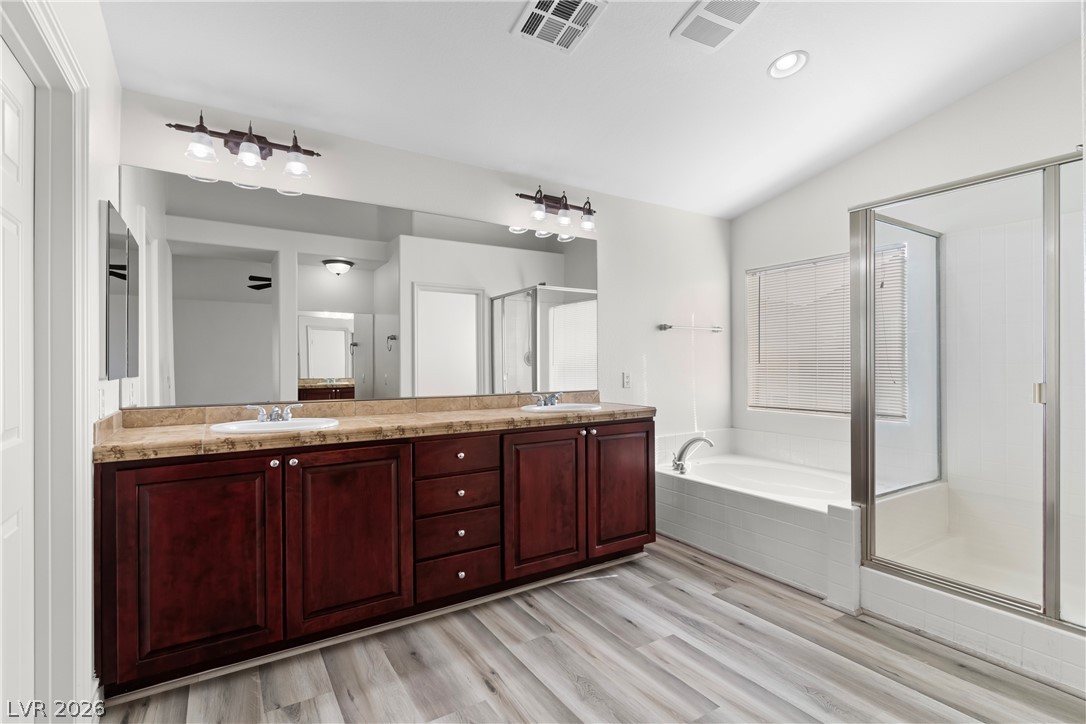 181 Short Ruff Way Las Vegas, NV 89148 - Photo 15 of 43 Full bath with double vanity, a shower stall, a bath, and light wood-type flooring