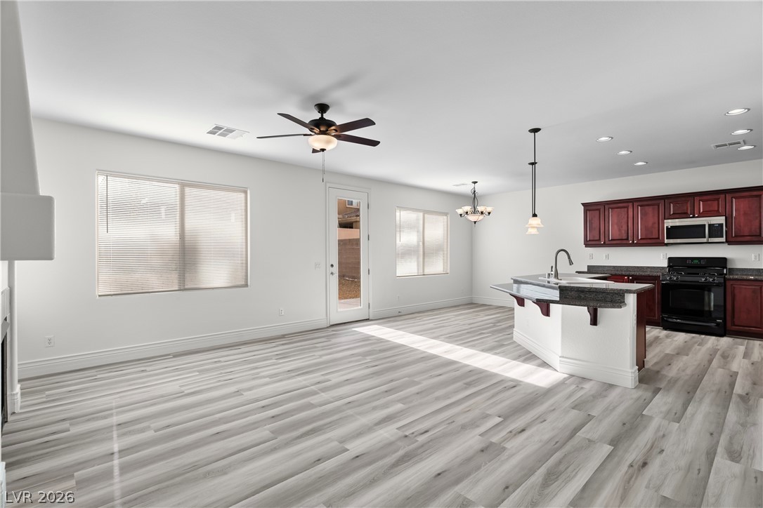 181 Short Ruff Way Las Vegas, NV 89148 - Photo 42 of 43 Kitchen featuring black gas stove, a kitchen breakfast bar, open floor plan, suspended lighting, and a ceiling fan