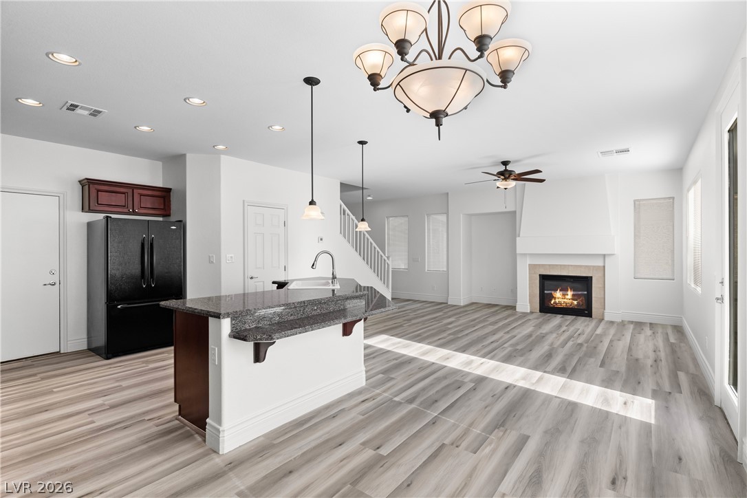 181 Short Ruff Way Las Vegas, NV 89148 - Photo 8 of 43 Kitchen with a kitchen bar, freestanding refrigerator, a tiled fireplace, hanging lights, and an island with sink