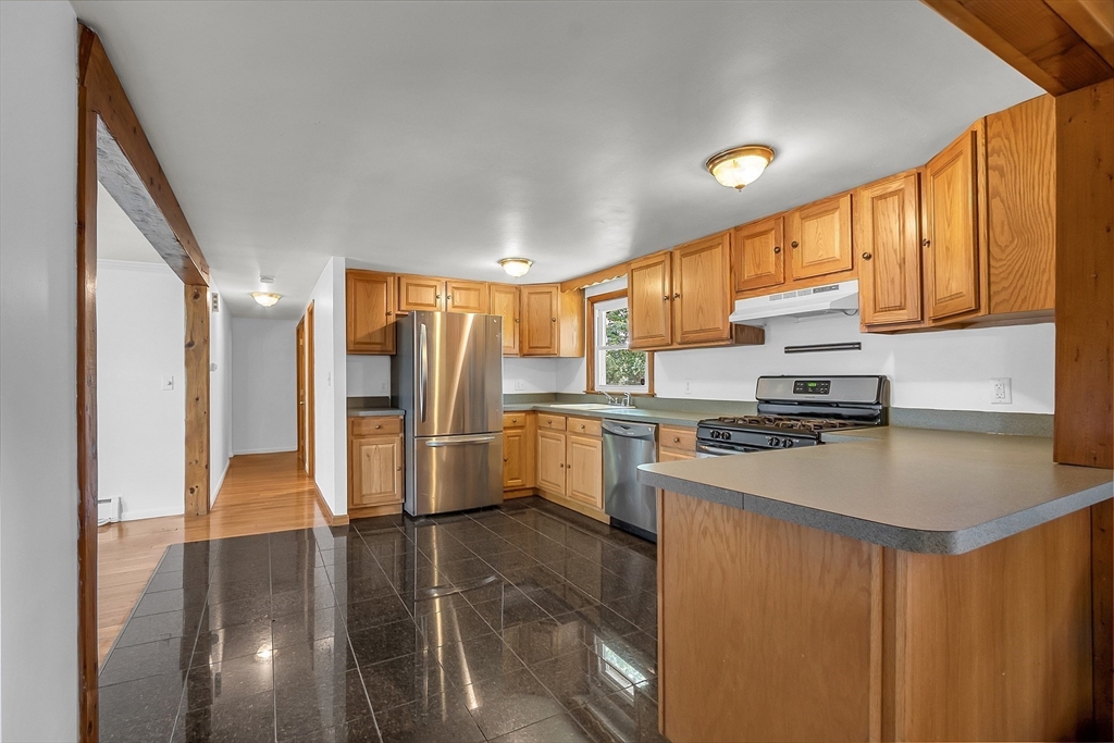36 Mill Street Maynard, MA 01754 - Photo 12 of 42 a kitchen with granite countertop a refrigerator a sink a stove and white cabinets with wooden floor