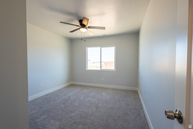 910 East Remington Road Cedar City, UT 84721 - Photo 8 of 29 Bright room featuring a ceiling fan with integrated lighting, a large window, light gray walls, white baseboards, and gray textured carpet