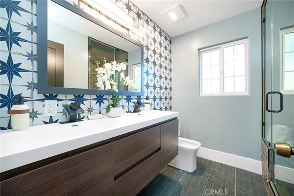 a bathroom with a sink a toilet a mirror and shower