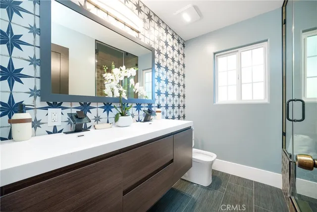 a bathroom with a sink a toilet a mirror and shower