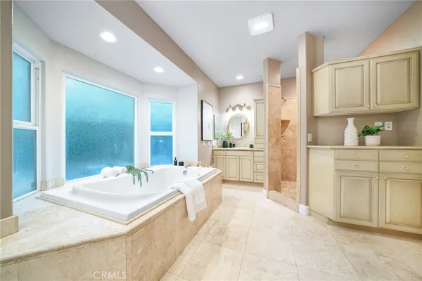 a spacious bathroom with a tub sink and mirror