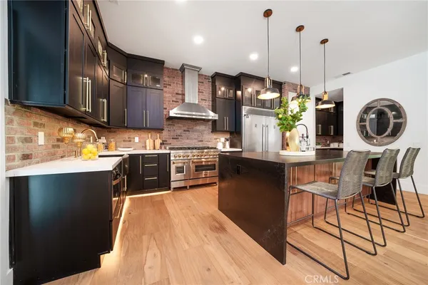 a kitchen with stainless steel appliances granite countertop a sink a stove and a wooden floors