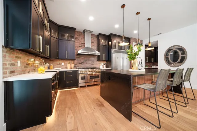 a kitchen with stainless steel appliances granite countertop a sink a stove and a wooden floors