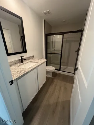 a bathroom with a granite countertop sink toilet and mirror