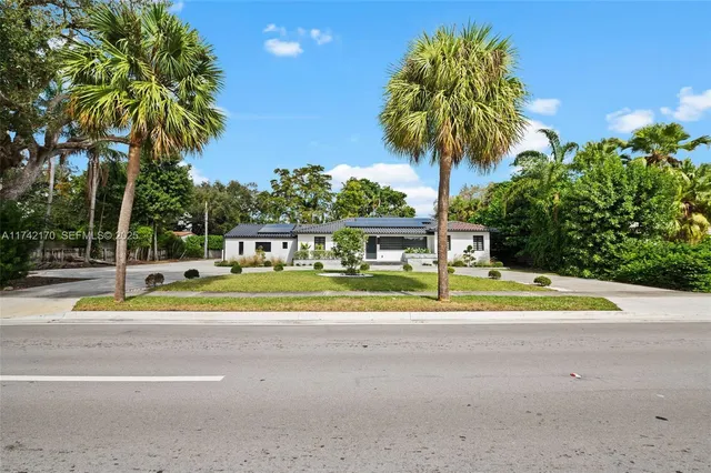 a view of a house with a yard and palm trees